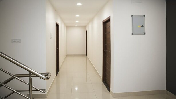Un pasillo con barandilla de metal, una puerta con panel de seguridad y suelo de baldosas.