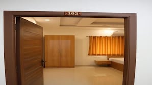 Una habitación con armario, cama, mesita de noche y cortina.