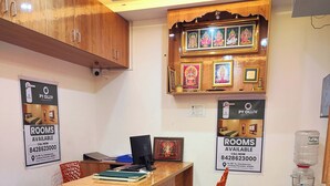 Un salón de conferencias con una mesa de madera, dos sillas naranjas, una computadora portátil, cuadros en la pared y un dispensador de agua.