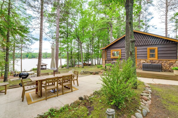 A cabin with a patio, outdoor seating, a grill, and a view of a lake. - Waterfront Tee Lake Cabin: Dock, Fire Pit + More! (Lewiston)