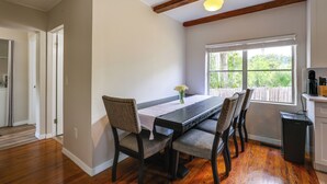 A dining area with a wooden table, chairs, a window with a view, and a ceiling light fixture.