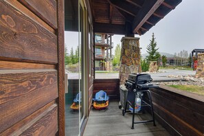 Ein Holzfassade mit einem Steinkamin, einem Grill und Blick auf ein mehrstöckiges Gebäude mit Balkonen.