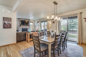 A modern kitchen with a stone backsplash, a dining area with a chandelier, and a large window with a view of trees. - Condo in the Heart of Dtwn Winter Park (Winter Park)