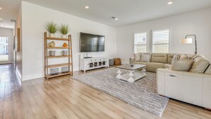 A modern living room with a sofa, TV, wooden shelving, and a patterned rug. - Close to Beach! Miramar Beach Haven w/ Pool Access (Miramar Beach)