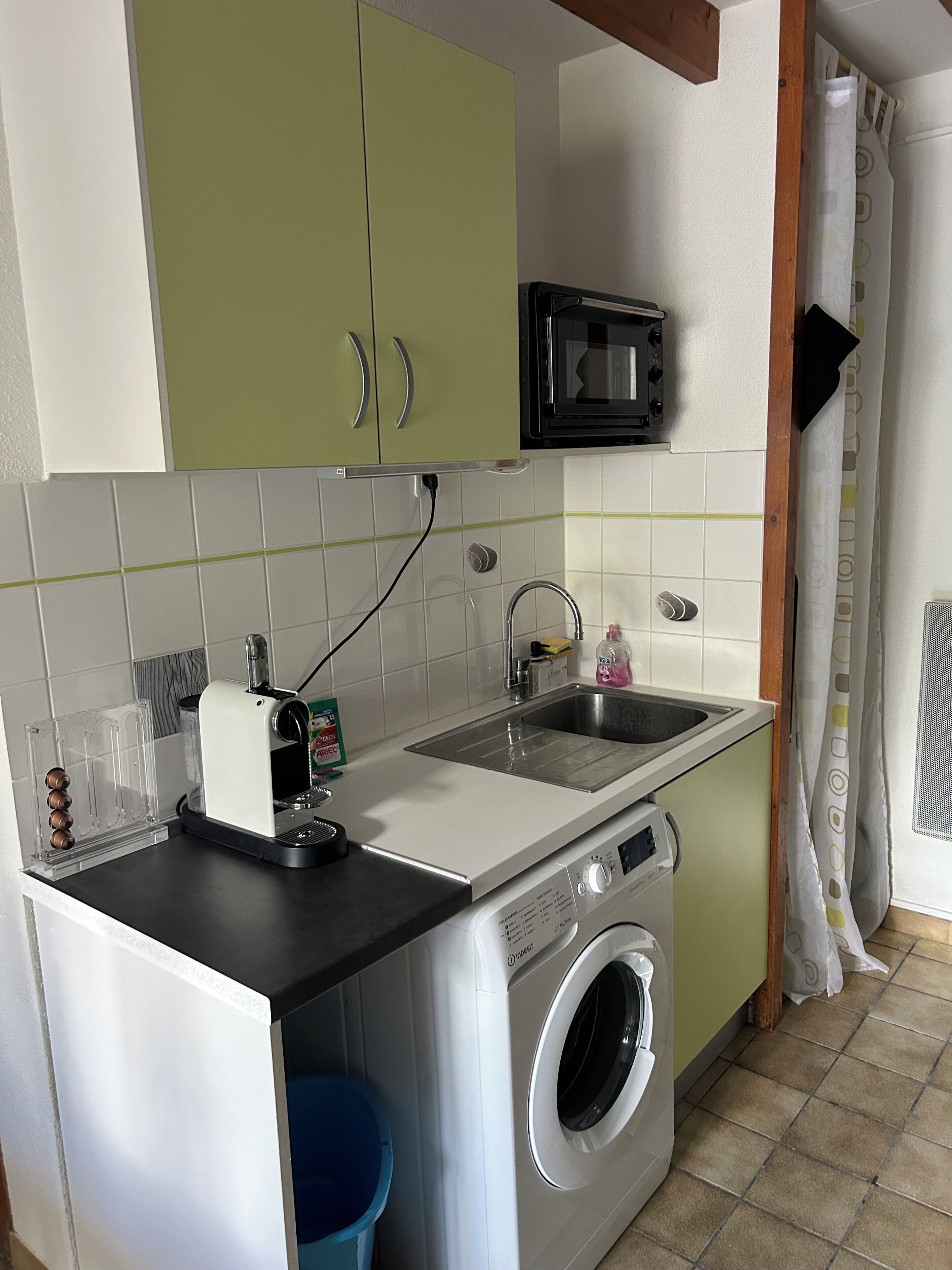 Eine kleine Küche mit Waschmaschine, Mikrowelle und Spüle.