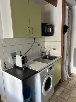 Une cuisine compacte équipée d’un lave-linge, d’un four à micro-ondes et d’un évier.