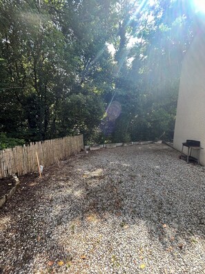 Une terrasse en gravier, une clôture en bois, une petite table et un mur.