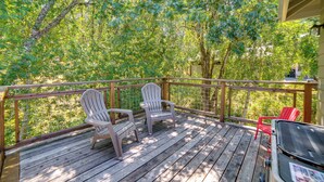Une terrasse en bois avec des fauteuils Adirondack et un barbecue.