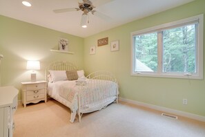 Ein Schlafzimmer mit Bett, Nachttisch, Kommode, Deckenventilator, Fenster und Wandregal.