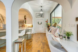 A spacious kitchen with white cabinetry, a dining area with a glass table, and a seating area with a view.