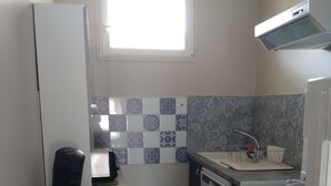 Ett kompakt kök med kylskåp, mikrovågsugn, diskmaskin och spis.