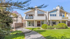A modern two-story house with a covered patio, a visible garage, and a well-maintained lawn. - Alpine Four with Views (Wānaka)