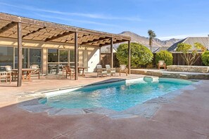 Ein Poolbereich mit Liegestühlen und einer überdachten Terrasse.