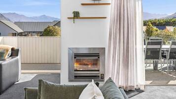 A modern outdoor living area with a fireplace, seating, and a view of mountains.