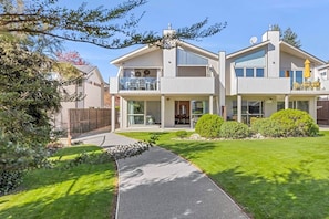 A modern two-story house with a covered patio, a visible garage, and a well-maintained lawn. - Alpine View Apartment for Six (Wanaka)