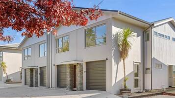 A modern two-story house with a garage, stone pillars, and a palm tree.