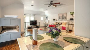 Uma sala de estar moderna com televisão, área de estar e espaço de jantar com ilha central.