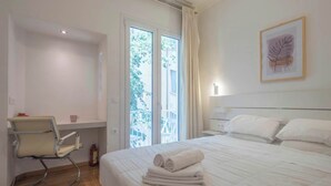 Habitación de hotel con cama, una silla, una ventana y un cuadro en la pared.