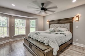 A bedroom with a large bed, a ceiling fan, and a dresser.
