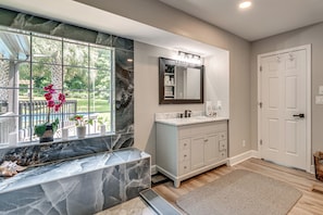 A bathroom with a marble vanity, a large mirror, and a view of the outdoors.