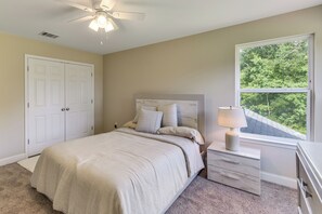 A bedroom with a bed, nightstand, lamp, window, and ceiling fan. - On Several Acres! Luxury Home in Prairieville (Prairieville)