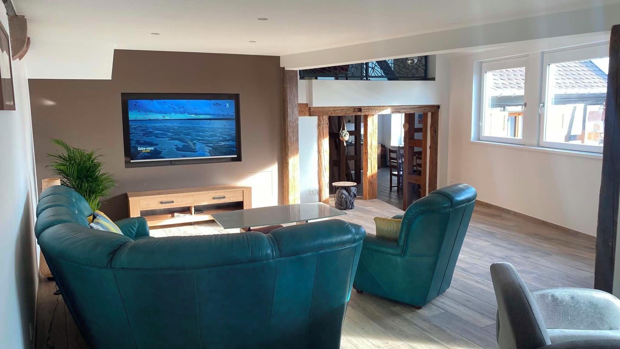 Una sala de estar con televisión, sofás color turquesa, una mesa de centro y un aparador de madera.