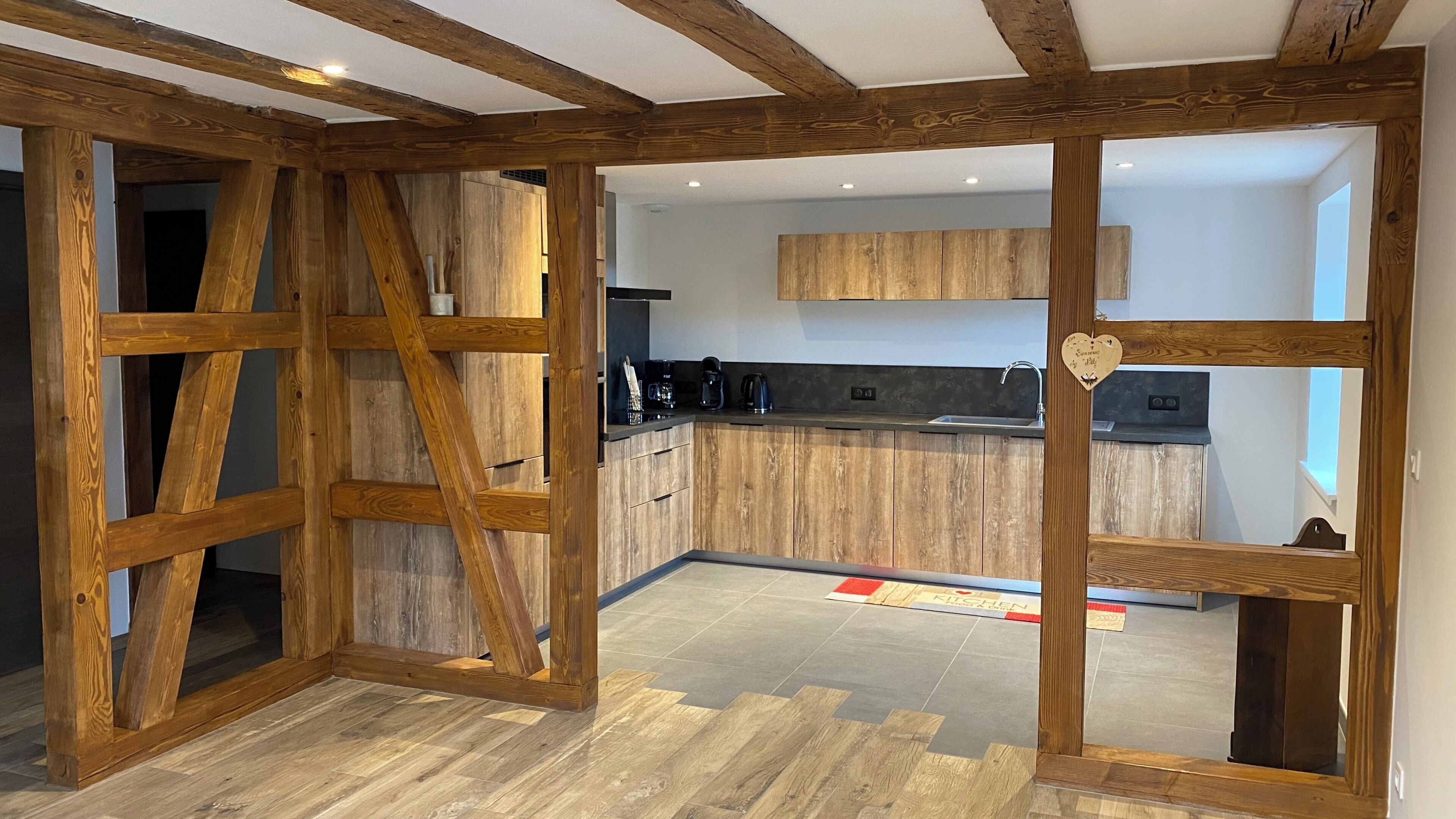 Une cuisine moderne avec des meubles en bois, un four encastré et une décoration en forme de cœur sur le mur.