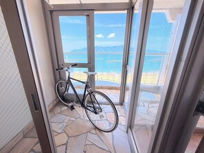 Una bicicleta apoyada contra una puerta de cristal con vistas a un balcón y un suelo de piedra.