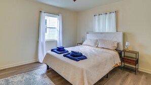 A bedroom with a bed, a nightstand, a lamp, a window with curtains, and a rug. - 14 Mi to Pittsburgh: Clairton Trailside Retreat (Clairton)