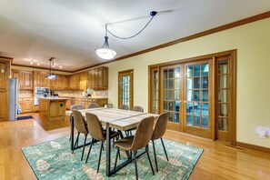 Une cuisine spacieuse avec des meubles en bois, une table à manger avec des chaises et une grande fenêtre avec des portes vitrées.