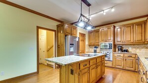 A spacious kitchen with wooden cabinets, a central island, stainless steel appliances, and a hanging light fixture. - Easy Hwy Access to Dtwn Atlanta! Group Retreat (Atlanta)