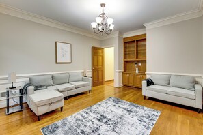 Een woonkamer met twee banken, een salontafel, een kroonluchter en houten vloeren.