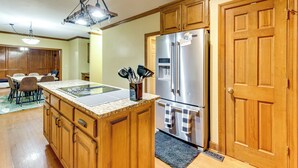 A kitchen with wooden cabinets, a stainless steel refrigerator, a granite countertop, and a dining area with chairs. - Easy Hwy Access to Dtwn Atlanta! Group Retreat (Atlanta)