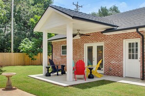A brick house with a covered patio, a door, and a fenced yard. - Walk to OU! Centrally Located Game-Day Getaway (Norman)
