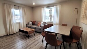 A modern living room with a sofa, coffee table, dining table, and chairs. - Jackalope Loft in Downtown Custer #2 (Custer)