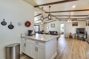 A kitchen with white cabinets, a granite countertop, a stainless steel trash can, and a ceiling fan. - 2 Mi to Colorado River! Family Home w/ Fenced Yard (Bullhead City)