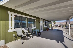 Eine überdachte Terrasse mit Sitzgelegenheiten, einem Mülleimer und Blick auf die Umgebung.