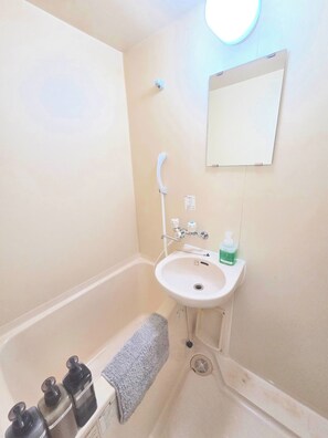 Een badkamer met een bad, wastafel, spiegel en toiletartikelen.