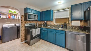 A compact kitchen with blue cabinets, stainless steel appliances, and a tiled backsplash. - Golf, Beaches & Sunshine! Pet-Friendly Naples Home (Naples)
