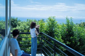 Ein Balkon mit Blick auf das Meer und üppiges Grün.