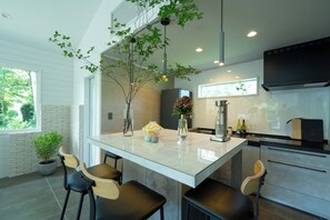 A modern kitchen with a central island, bar stools, a large window, and a hanging plant. - Dogfriendly vacation rental Room only Maximum / Ito City Shizuoka (Ito City)
