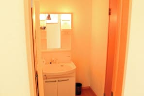 A small bathroom with a sink, mirror, and a trash bin.