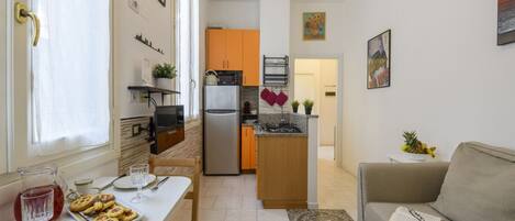 Un espacio habitable pequeño con kitchenette, comedor y sofá.