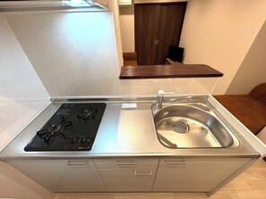 Uma cozinha compacta com fogão embutido, pia de aço inoxidável e bancada pequena.