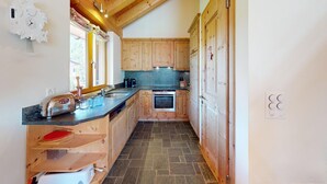 A kitchen with wooden cabinets, a built-in oven, a sink, and a countertop with various items. - Chesa Iva is situated in one of the most sought-after residential locations in C (Celerina/Schlarigna)