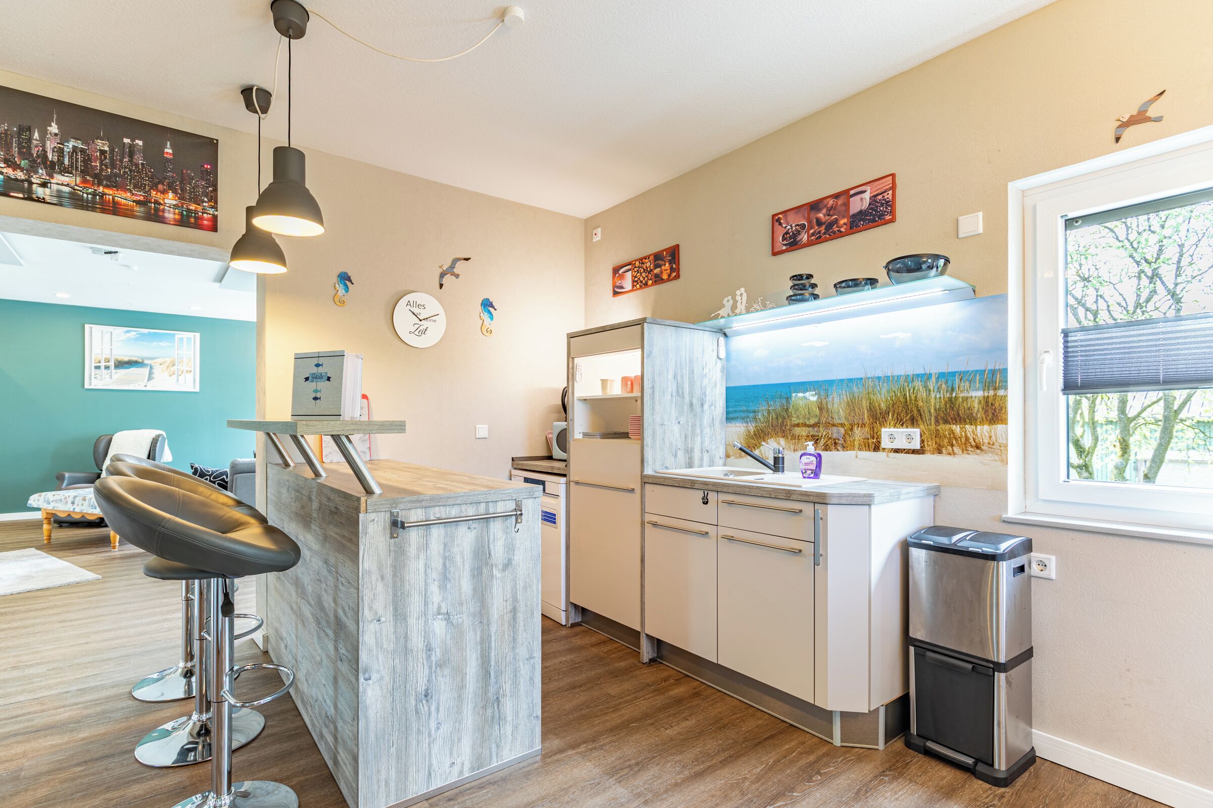 A modern kitchen with a bar area, wooden flooring, and a view of the outdoors.