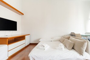 Ein Hotelzimmer mit Bett, Fernseher, Schreibtisch aus Holz und Stuhl.