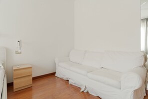 Ein weißes Sofa, ein Nachttisch aus Holz und eine Steckdose in einem Zimmer mit Holzböden.