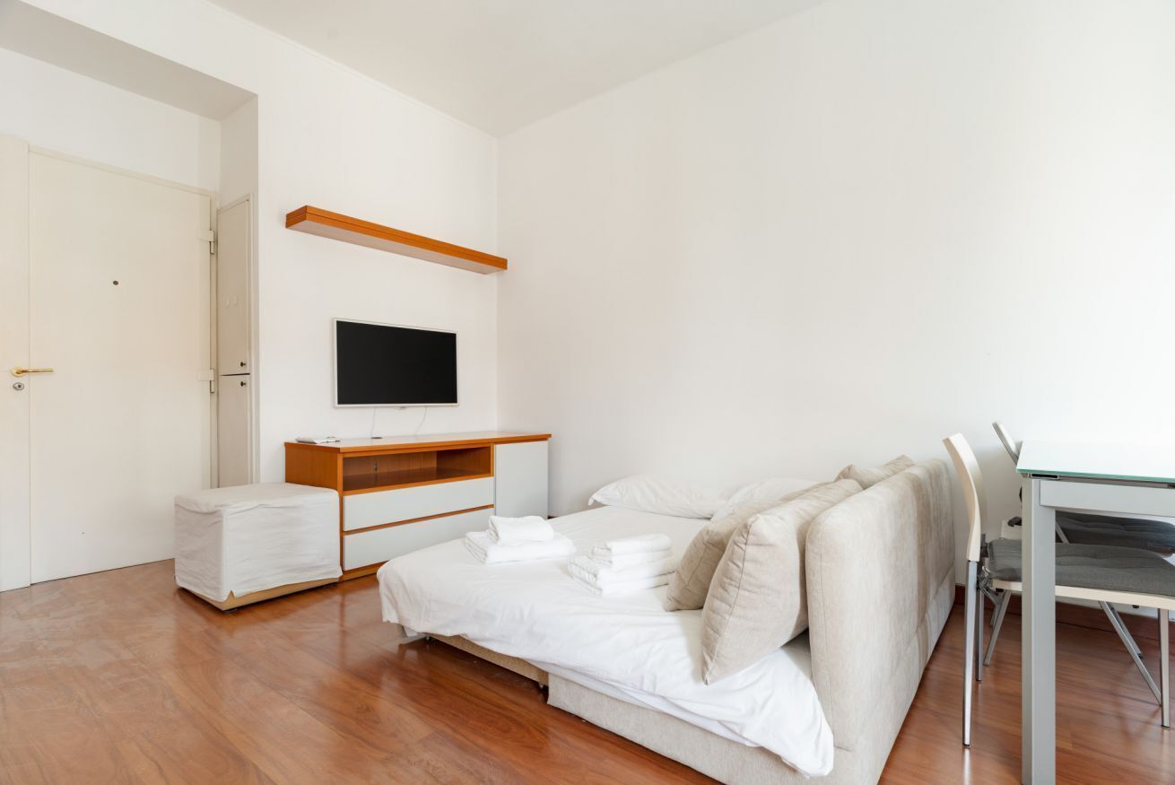 A bedroom with a bed, a TV, a desk, and a chair.