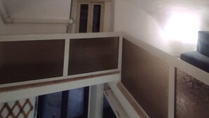 Una habitación con techo inclinado, una ventana con marco de madera y un panel decorativo en la pared.
